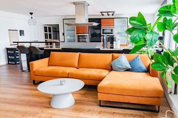 A modern living room with a sectional sofa, a coffee table, and a kitchen in the background.