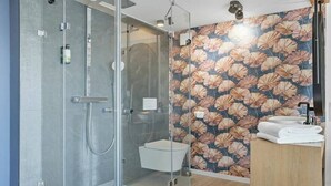 Um banheiro moderno com chuveiro de vidro, vaso sanitário e pia com bancada de madeira.