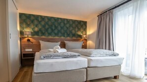 Uma cama de casal com cabeceira, duas mesas de cabeceira e uma parede com padrão geométrico.