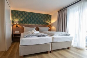 Una cama doble con cabecera, dos mesitas de noche y una pared con diseño geométrico.