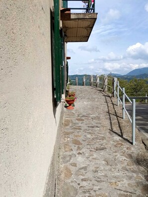 Un camí de pedra que condueix a un edifici amb una porta verda i un balcó.