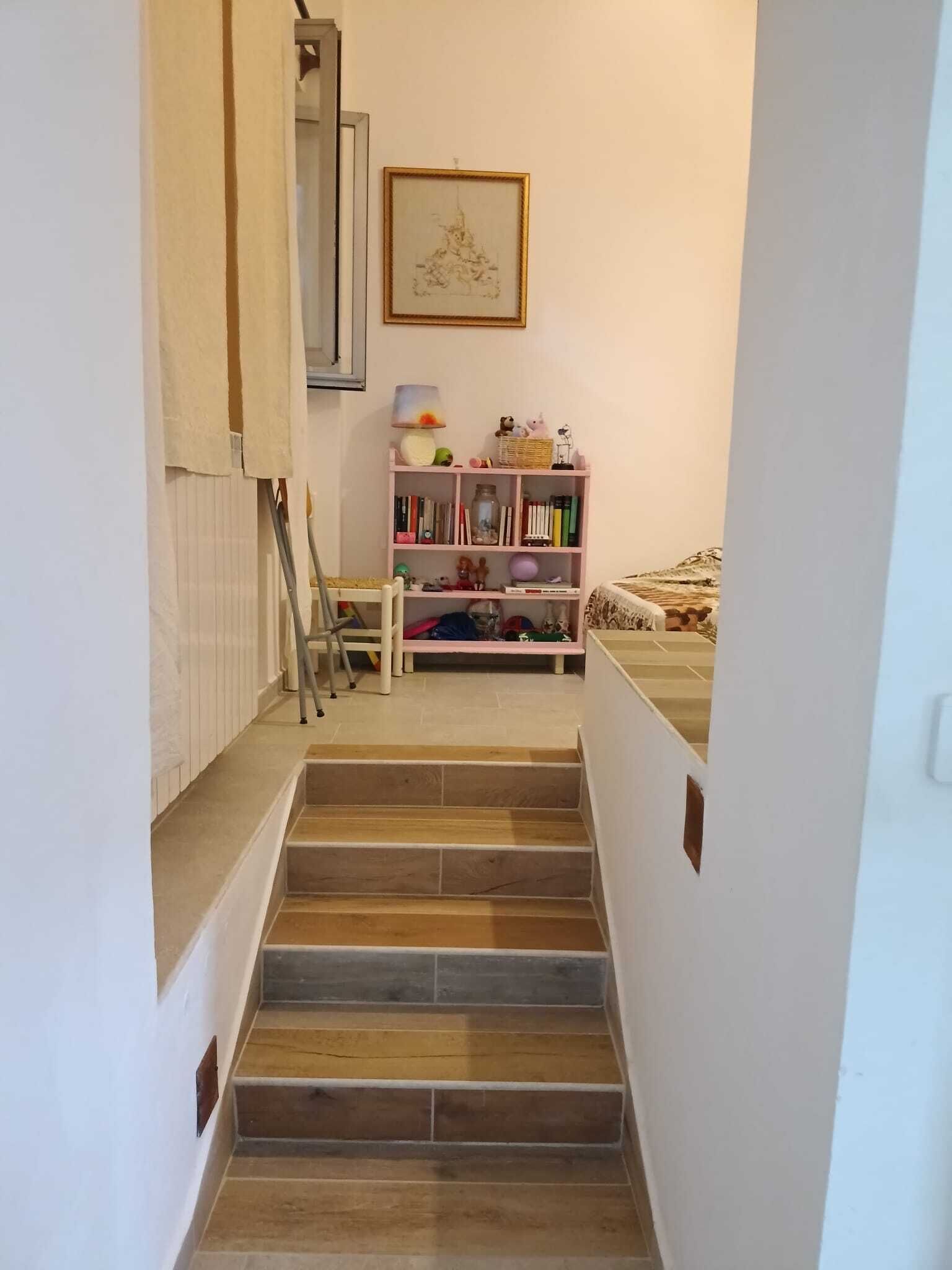Una scala conduce a una camera da letto con un letto e una libreria.