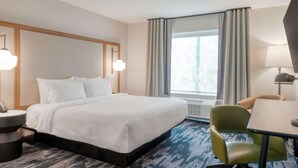 Ein Hotelzimmer mit Bett, Schreibtisch, Stuhl und einem Fenster mit Vorhängen.