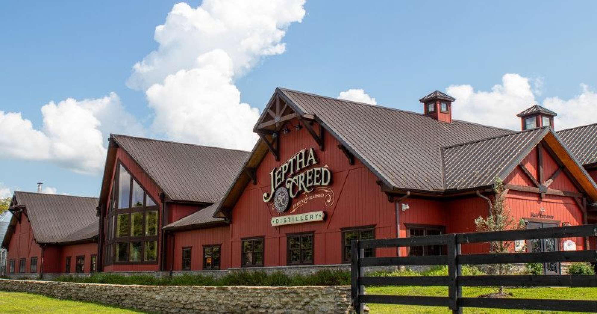 A red building with a sign that reads 'Jeptha Creed Distillery.'