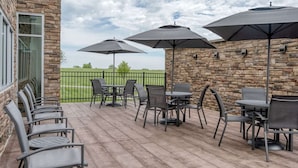 Eine Terrasse im Freien mit Steinmauern, mehreren Tischen und Stühlen sowie Sonnenschirmen.