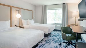 Ein Hotelzimmer mit zwei Betten, einem Schreibtisch, einem Stuhl, einem Fernseher und einem Fenster mit Vorhängen.