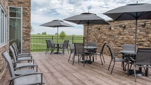 Eine Terrasse im Freien mit Steinmauern, mehreren Tischen und Stühlen sowie Sonnenschirmen.