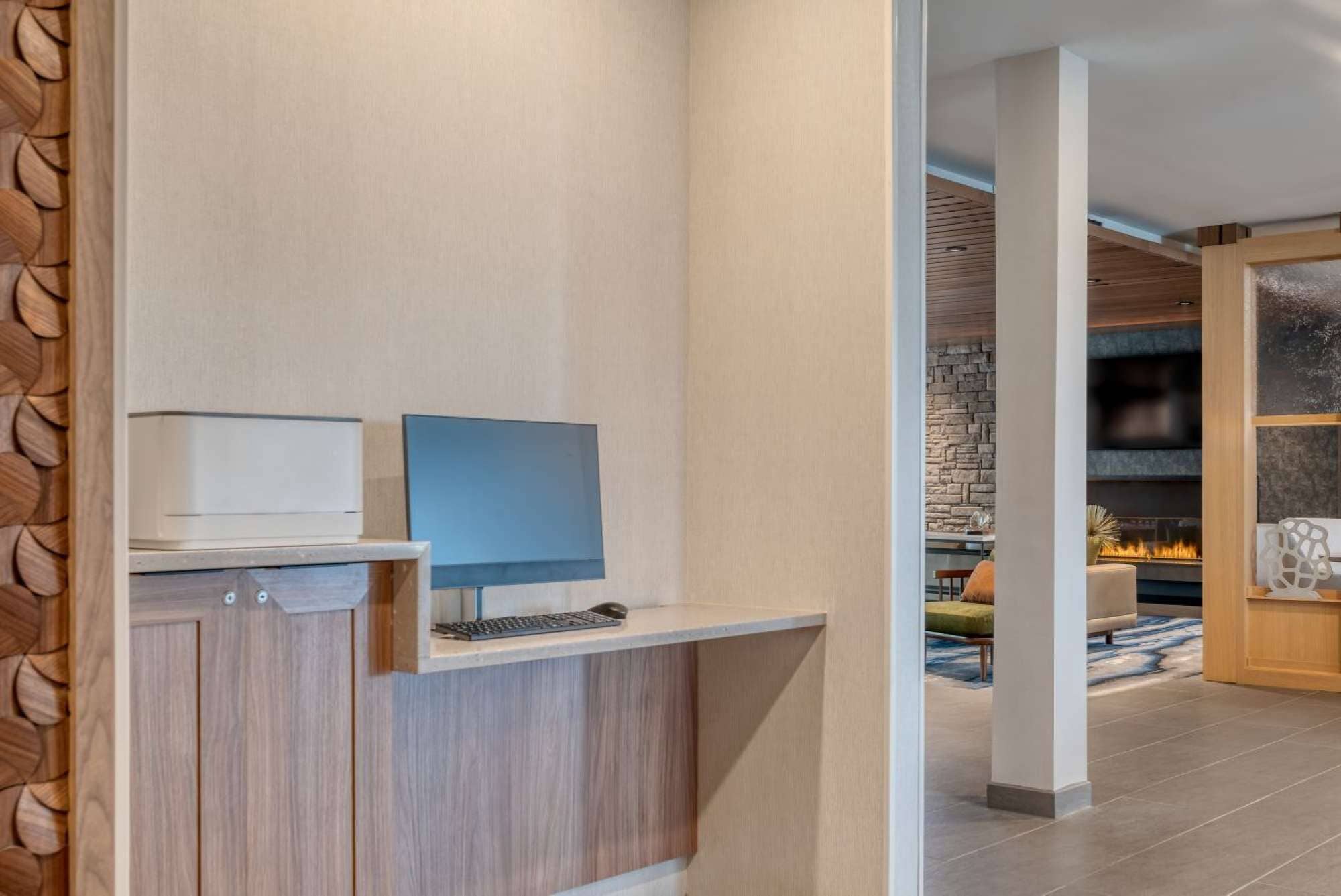 Un interior moderno con un escritorio de madera, un televisor de pantalla plana y una pared de piedra al fondo.