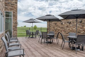 An outdoor patio with stone walls, multiple tables and chairs, and umbrellas. - Minutes to KFC Yum! Center + Free Breakfast & Gym (Shelbyville)