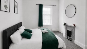A bedroom with a bed, a fireplace, and a window with curtains. - House Sleeps 6 With Garden (Coventry)