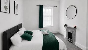 Un dormitorio con cama, chimenea y ventana con cortinas.