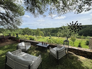 Een terras met rieten meubilair en uitzicht op een weelderig landschap.