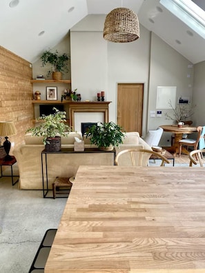 Un soggiorno spazioso con soffitto alto, camino e zona pranzo con tavolo in legno.