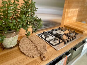 A kitchen with a gas stove, a woven placemat, and a potted plant. - A spacious one bed farm cottage, perfect for a relaxing getaway (Clonakilty)