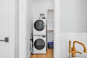 A laundry room with stacked washing machines and a gold faucet. - Three King Suites, Lake Views & 20+ Resort Amenities in Cinnamon Shore South (Port Aransas)
