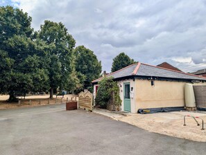 A small building with a red door, a paved area, and trees in the background. - Comfortable studio with free parking (Berkshire)