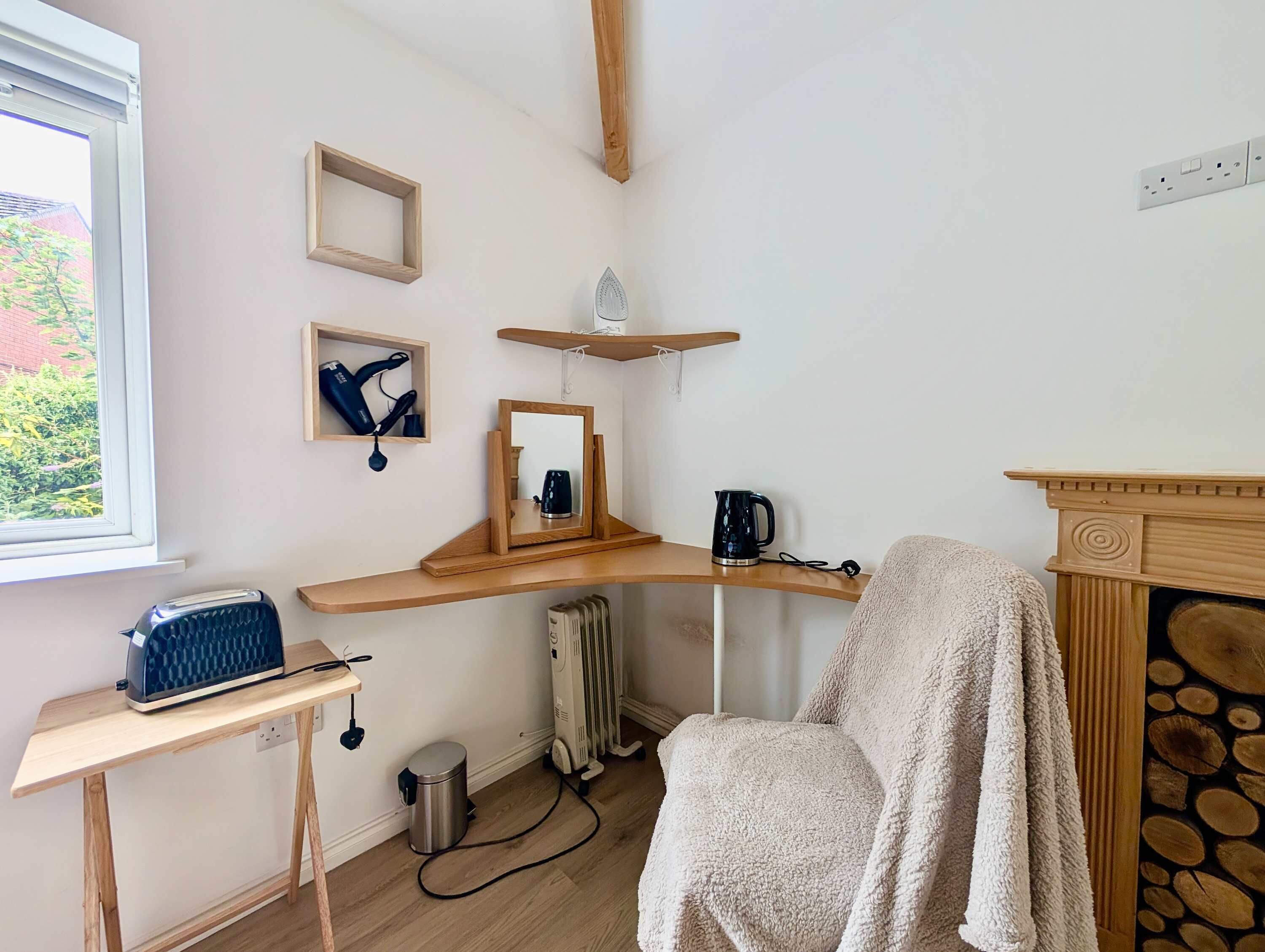 A room with a wooden desk, a radiator, a chair with a towel, and a fireplace.