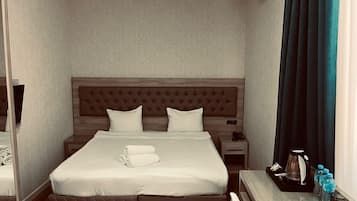 Una habitación de hotel con cama, mesitas de noche, un espejo, una ventana con cortinas y un aire acondicionado de pared.