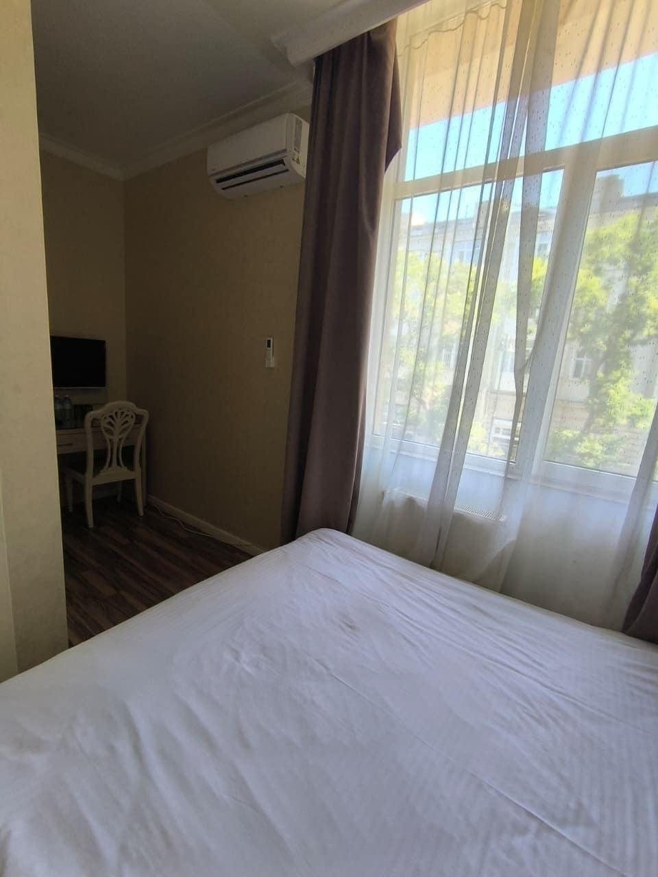 Una habitación de hotel con una cama, un escritorio, una silla y una ventana con cortinas.