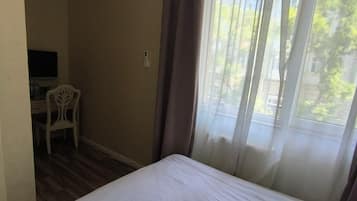 Una habitación de hotel con una cama, un escritorio, una silla y una ventana con cortinas.