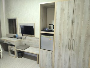 A room with a wooden desk, a television, a small refrigerator, and a cabinet. - Empire Hotel Baku (Baku)