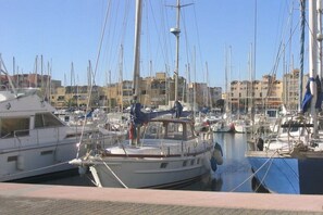 A marina with multiple boats docked, a clear sky, and buildings in the background. - Comfortable atmosphere at the bathing lagoon (Gruissan-Les Ayguades)