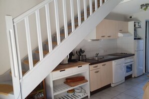 A kitchen with white cabinetry, a wooden staircase, and a white dishwasher. - Comfortable atmosphere at the bathing lagoon (Gruissan-Les Ayguades)