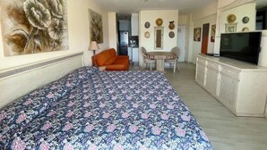 Quarto com uma cama, uma cadeira, uma mesa, uma televisão e um ventilador de teto.
