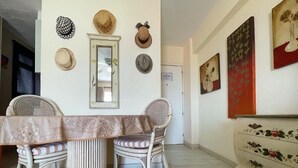 Uma sala de jantar com mesa e cadeiras, um espelho e chapéus pendurados na parede.