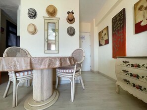 A dining area with a table and chairs, a mirror, and wall-mounted hats. - Edificio Arco (Arona)