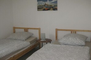 A room with two single beds, a small round table, and a wall-mounted picture. - Les Terrasses de la Mer No. 03 (Saint Pierre la Mer)