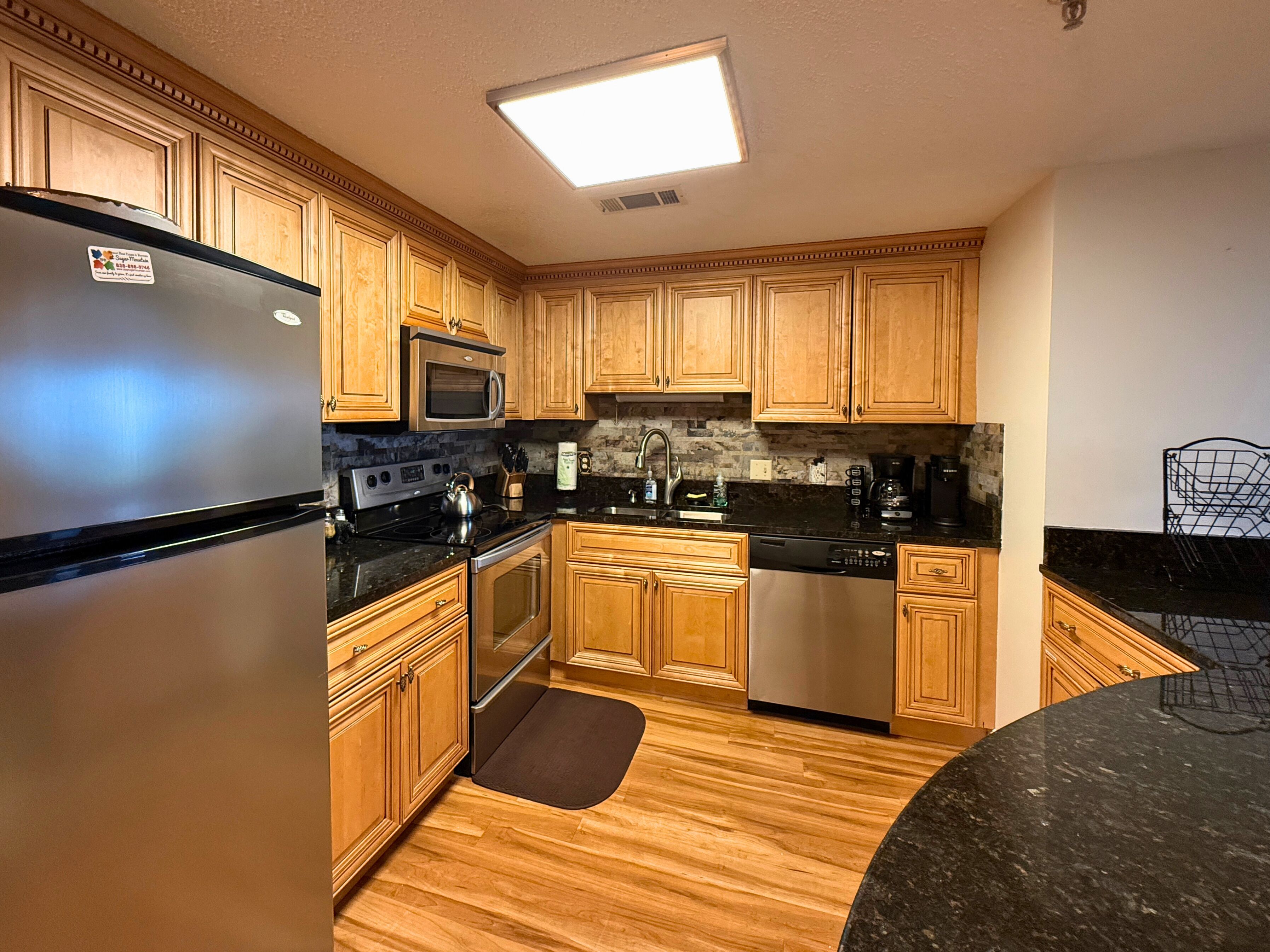 A kitchen with wooden cabinets, a stainless steel refrigerator, a microwave, a stove, and a dishwasher.