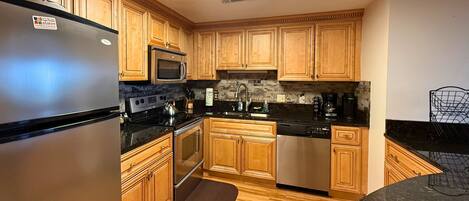A kitchen with wooden cabinets, a stainless steel refrigerator, a microwave, a stove, and a dishwasher.