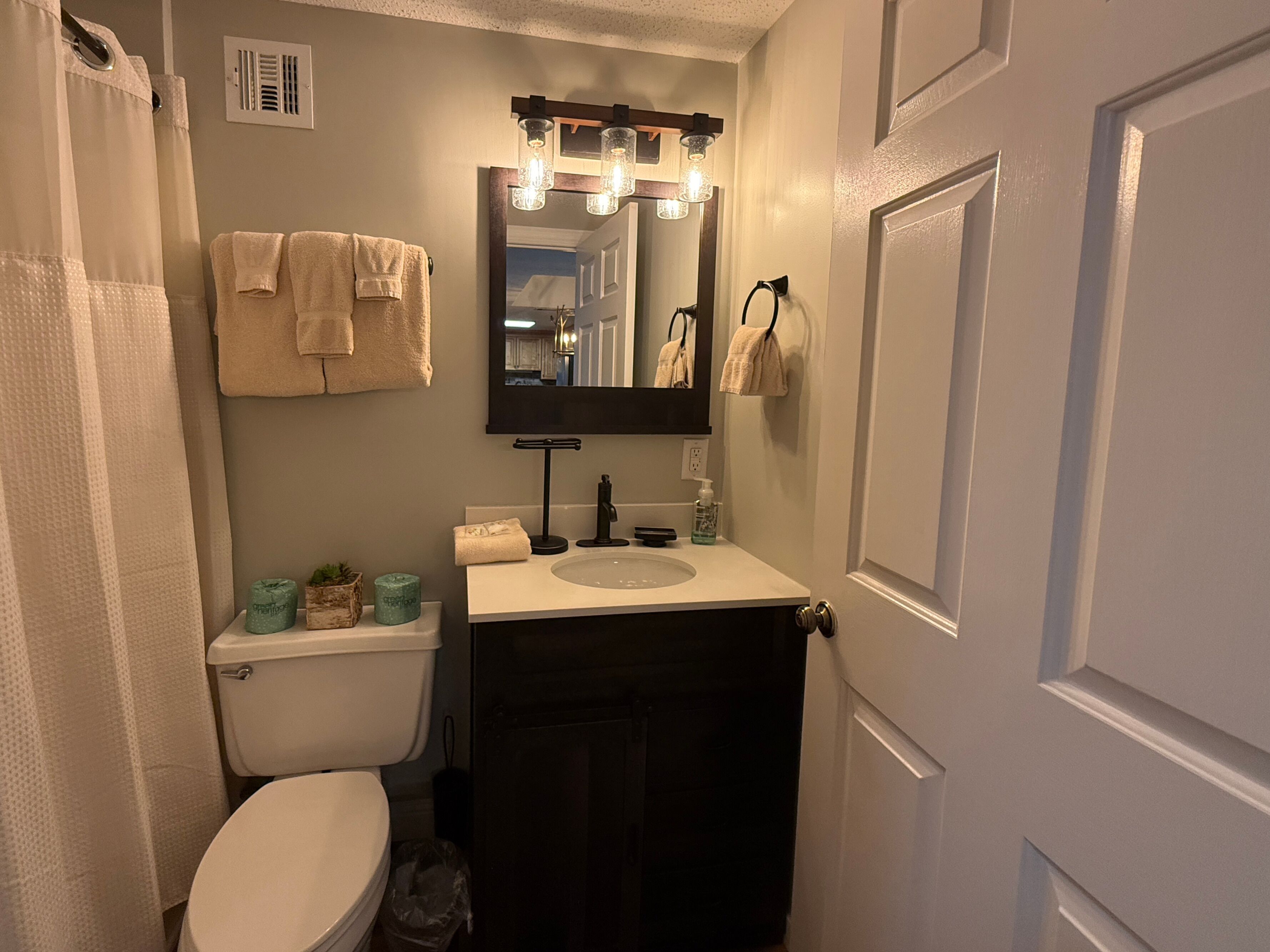 A bathroom with a toilet, sink, mirror, and towel rack.