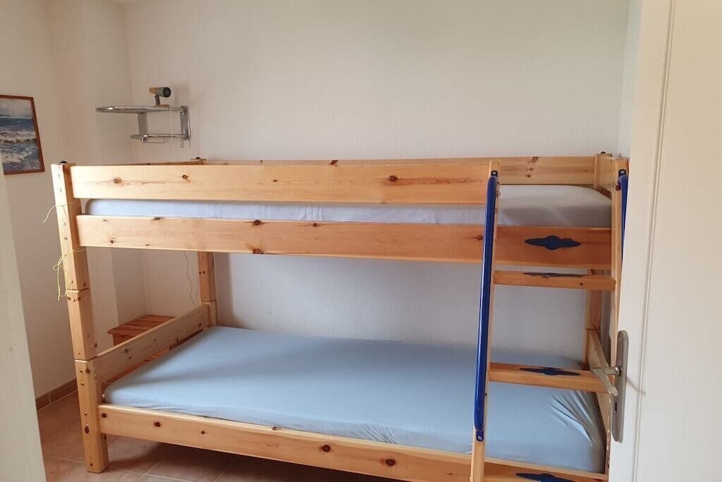 A bunk bed with a shelf above and a door on the right.