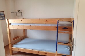Una cama individual superpuesta con un estante arriba y una puerta a la derecha.