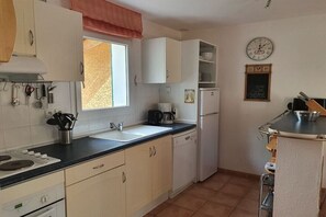 Una cocina compacta con armarios blancos, un lavamanos, una estufa y un refrigerador.