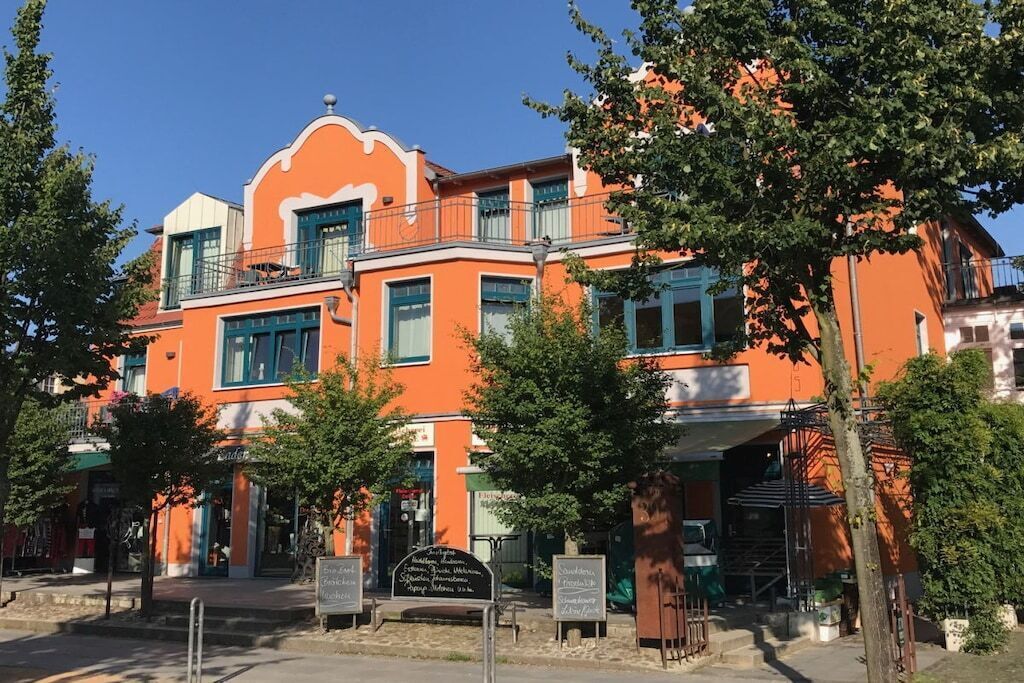 Een gebouw met een opvallende oranje gevel, meerdere ramen en een balkon.
