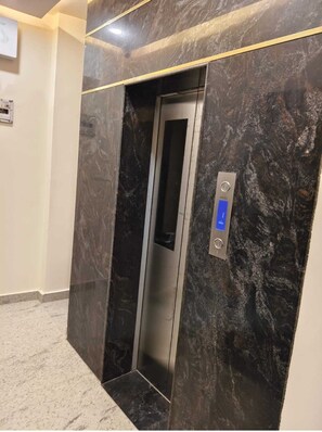 An elevator with a digital display, marble walls, and a carpeted floor. - ANJU VILLA (Varanasi)