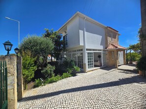 A building with a stone facade, a tiled roof, and a cobblestone driveway. - Casa Forever Young — Perfect 4-Bedroom House with Pool in Fabulous Sesimbra (SESIMBRA)