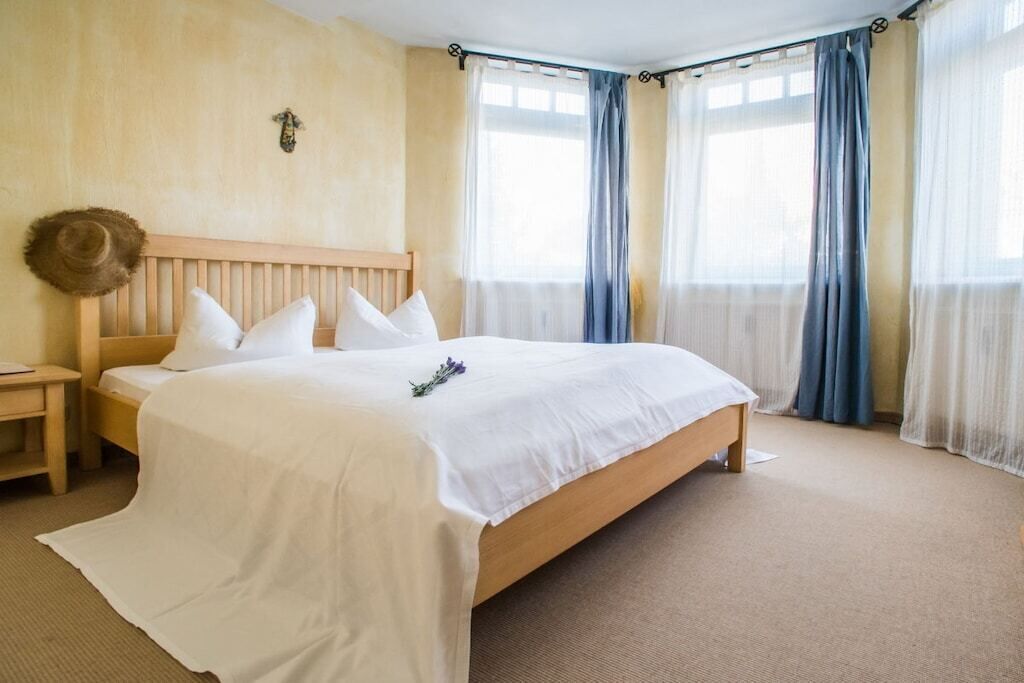 Una camera da letto con un letto in legno, biancheria da letto bianca, un comodino e un punto luce a parete.