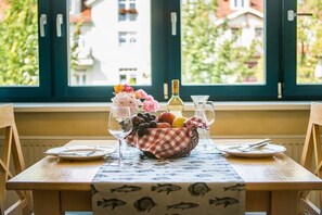 A dining table with a checkered tablecloth, a fruit basket, wine glasses, and plates set for two. - Tower House Holiday Apartment 5 (Kühlungsborn)
