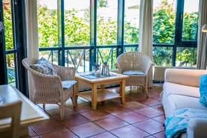 A room with a large window, wicker furniture, a white sofa, and a tiled floor. - Tower House Holiday Apartment 4 (Kühlungsborn)