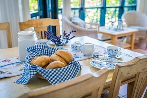 A dining table with a basket of bread, a vase with flowers, and tea set. - Tower House Holiday Apartment 4 (Kühlungsborn)