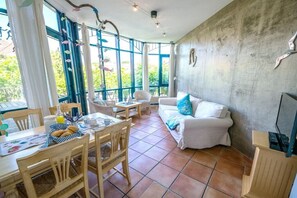 Àmplia zona d'estar amb taula de menjador, cadires, sofà i televisió.