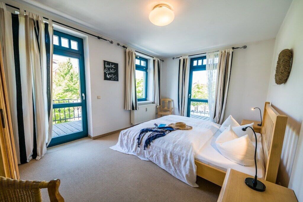 A bedroom with a bed, a bedside table, a chair, and a window with curtains.