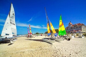 A beach with several sailboats anchored in the sand, a clear blue sky, and a building in the background. - Tower House Holiday Apartment 3 (Kühlungsborn)