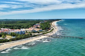 A coastal town with a beach, a pier, and buildings with red roofs. - Tower House Holiday Apartment 3 (Kühlungsborn)