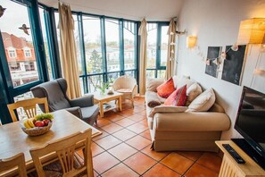 Una sala de estar con un sofá, una mesa con fruteros y un televisor.