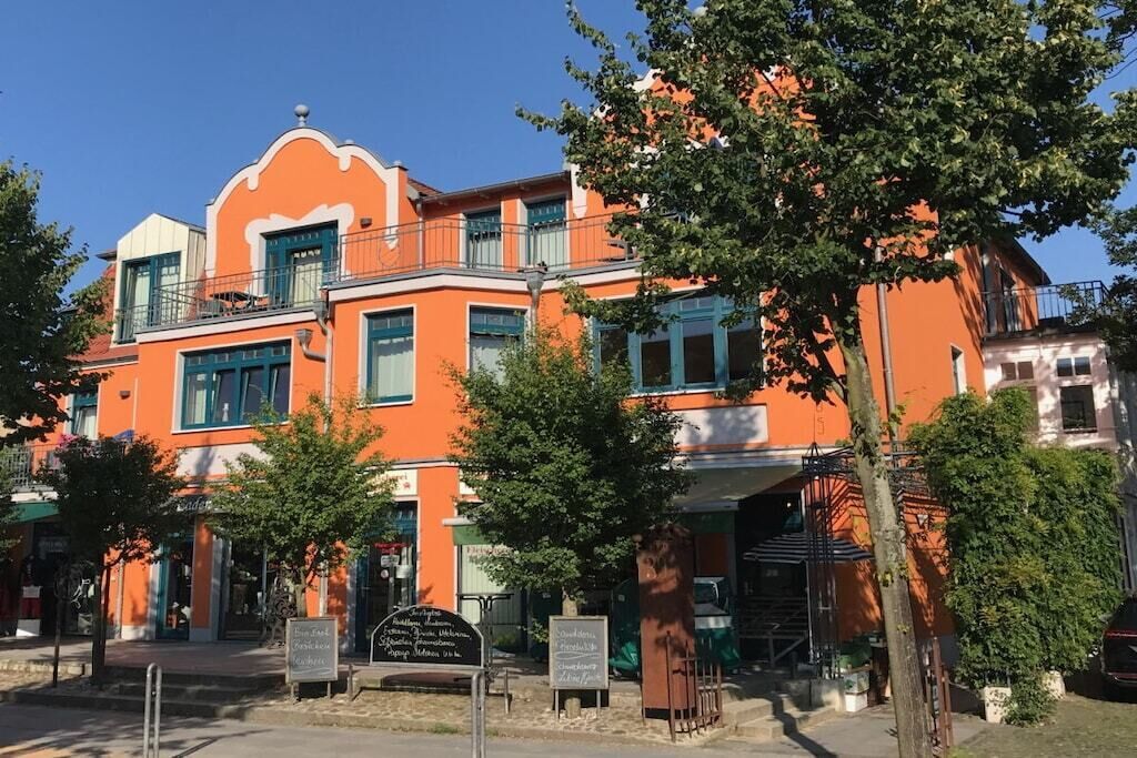 Un edificio a più piani con una facciata arancione caratteristica, balconi e una insegna.